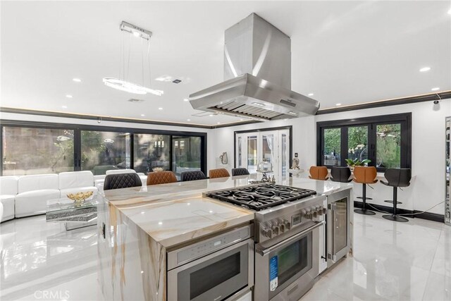 kitchen featuring island range hood, a kitchen island, pendant lighting, stainless steel appliances, and ornamental molding