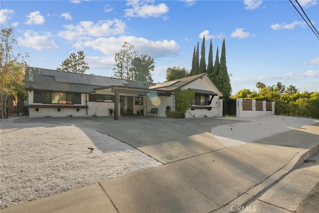 view of front of home with roof mounted solar panels, fence, a gate, and driveway