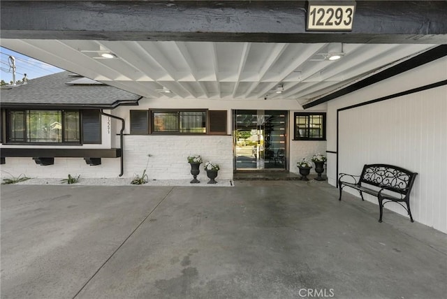 property entrance with roof with shingles and a patio area