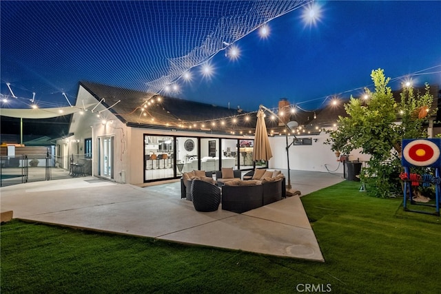 back house at twilight featuring a yard and a patio area