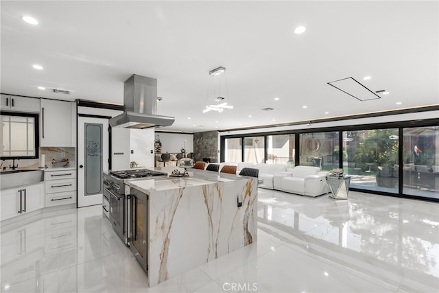 kitchen with light stone counters, pendant lighting, island exhaust hood, and plenty of natural light