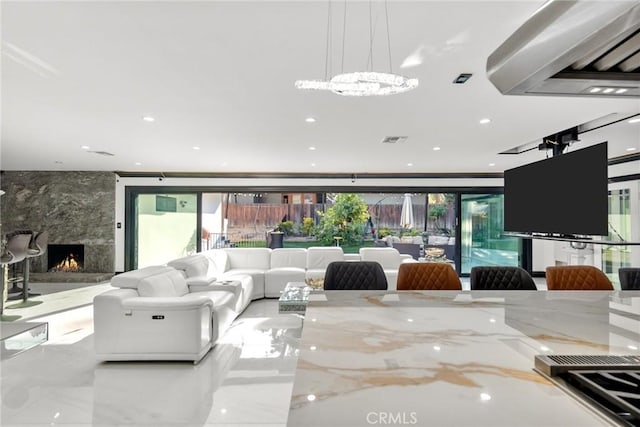living room featuring a high end fireplace, recessed lighting, and visible vents