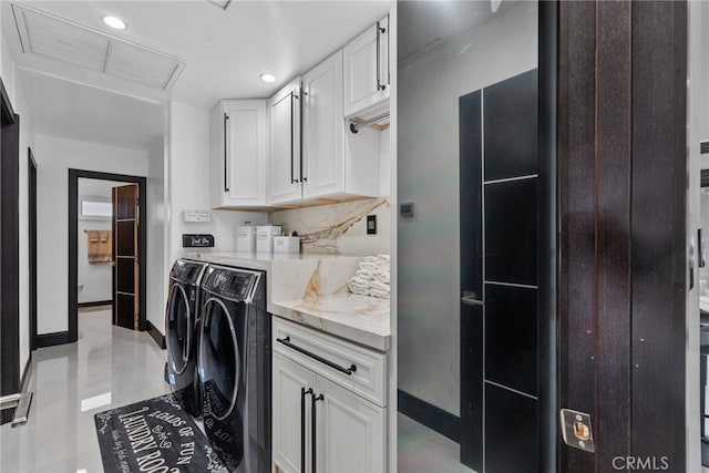 clothes washing area with separate washer and dryer and cabinets