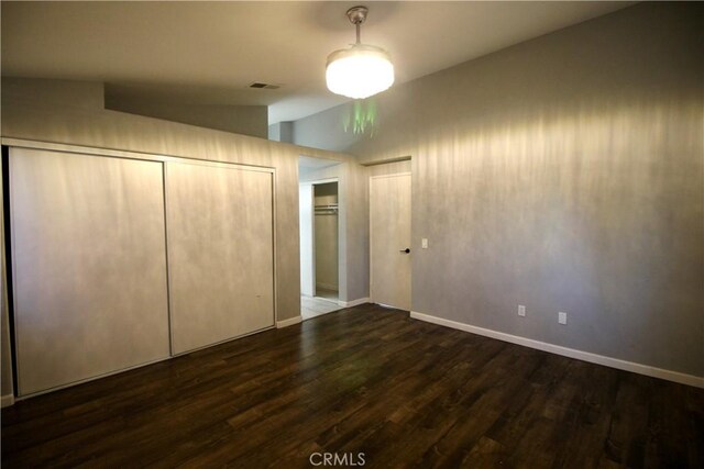 unfurnished bedroom featuring dark hardwood / wood-style floors and lofted ceiling