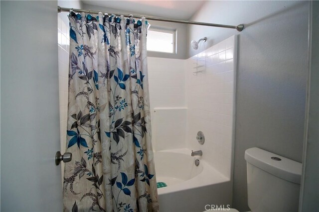 bathroom featuring toilet and shower / bathtub combination with curtain