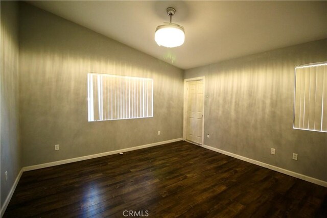 spare room with dark hardwood / wood-style floors and lofted ceiling