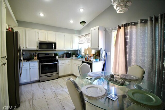 kitchen with white cabinetry, sink, stainless steel appliances, and vaulted ceiling