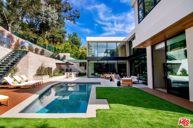 view of swimming pool featuring outdoor lounge area, a patio area, and a lawn