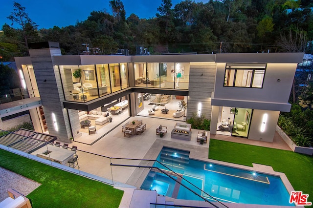 back of house featuring a patio area, a balcony, a lawn, outdoor lounge area, and exterior kitchen