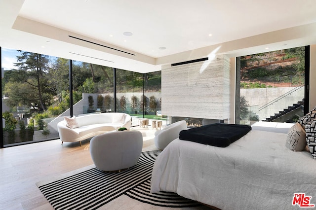 bedroom with a wall of windows and light hardwood / wood-style floors