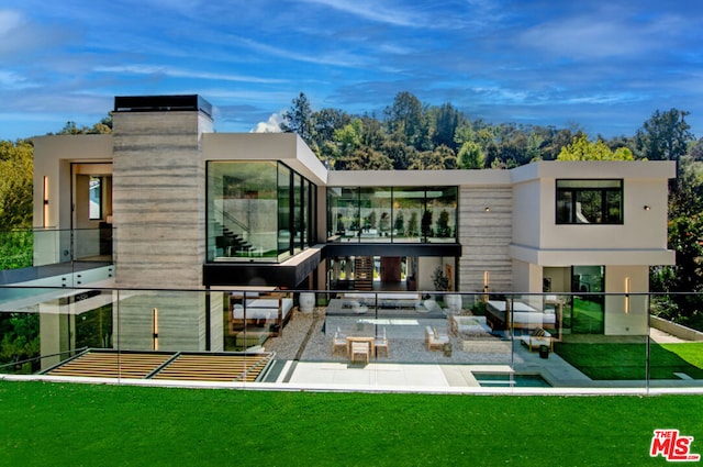 rear view of house with a sunroom, a lawn, and a patio area