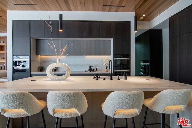 kitchen featuring wood ceiling, black double oven, and an island with sink