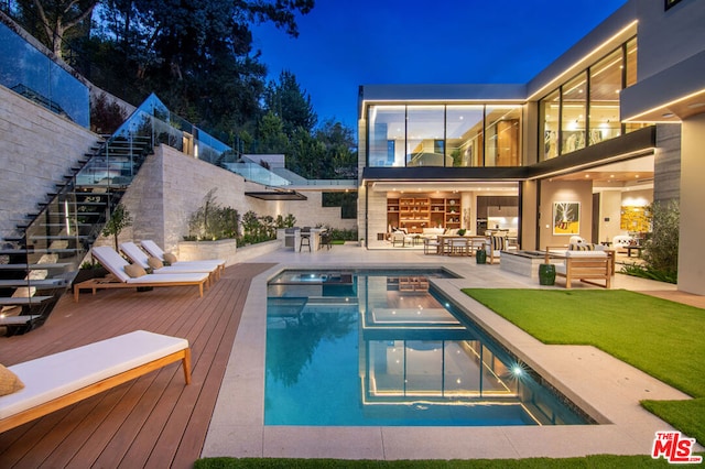 pool at twilight featuring a wooden deck, an outdoor living space, and an in ground hot tub