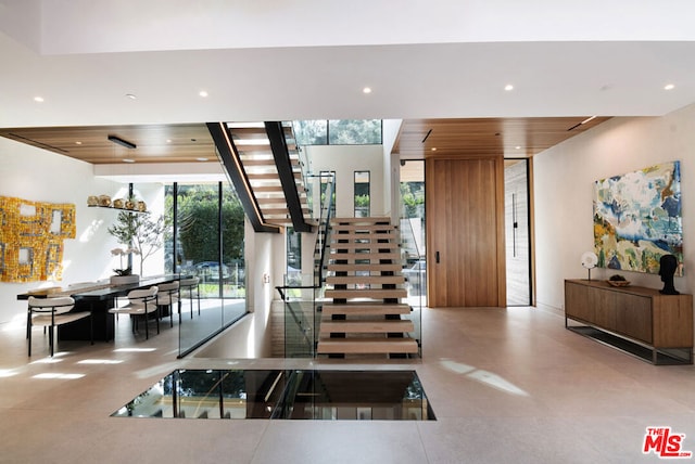 stairway with a wall of windows, plenty of natural light, and wooden ceiling