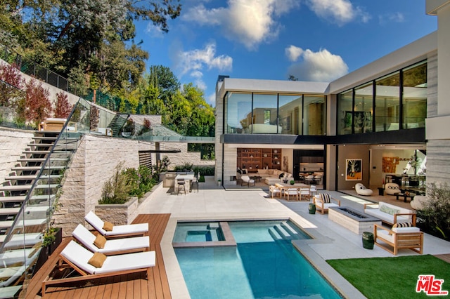 back of house with a pool with hot tub, a patio area, and an outdoor fire pit