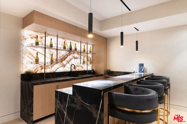 bar featuring decorative light fixtures, sink, and light wood-type flooring