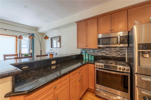 637 S Grand Ave Unit 4, San Pedro, CA 90731 - kitchen featuring stainless steel appliances, brown cabinets, dark stone countertops, backsplash, and a peninsula