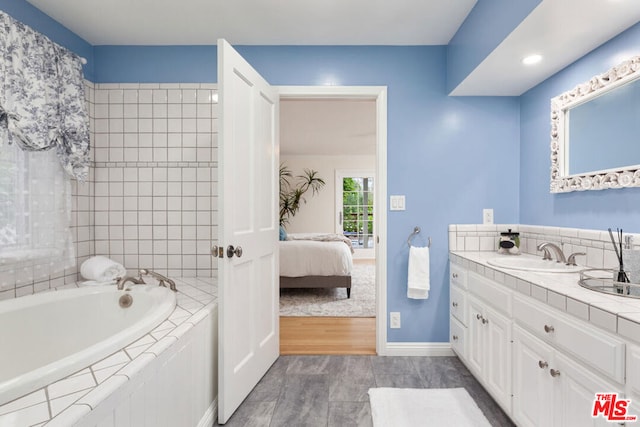 bathroom featuring vanity, hardwood / wood-style floors, and a bath