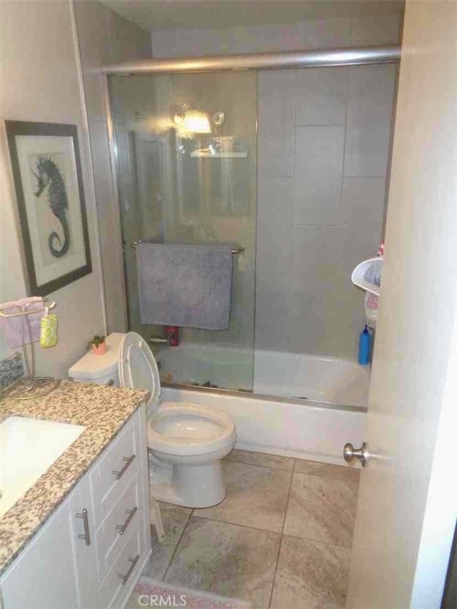 full bathroom featuring tile patterned floors, vanity, bath / shower combo with glass door, and toilet