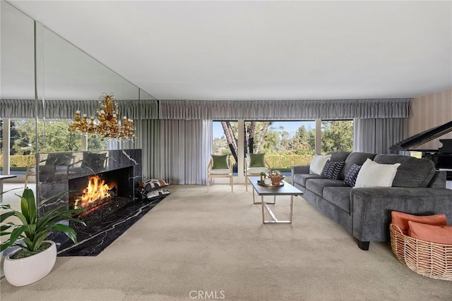 living room with an inviting chandelier, light colored carpet, a high end fireplace, and plenty of natural light