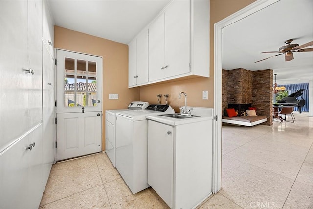 laundry room with sink, washer and clothes dryer, ceiling fan, cabinets, and a large fireplace