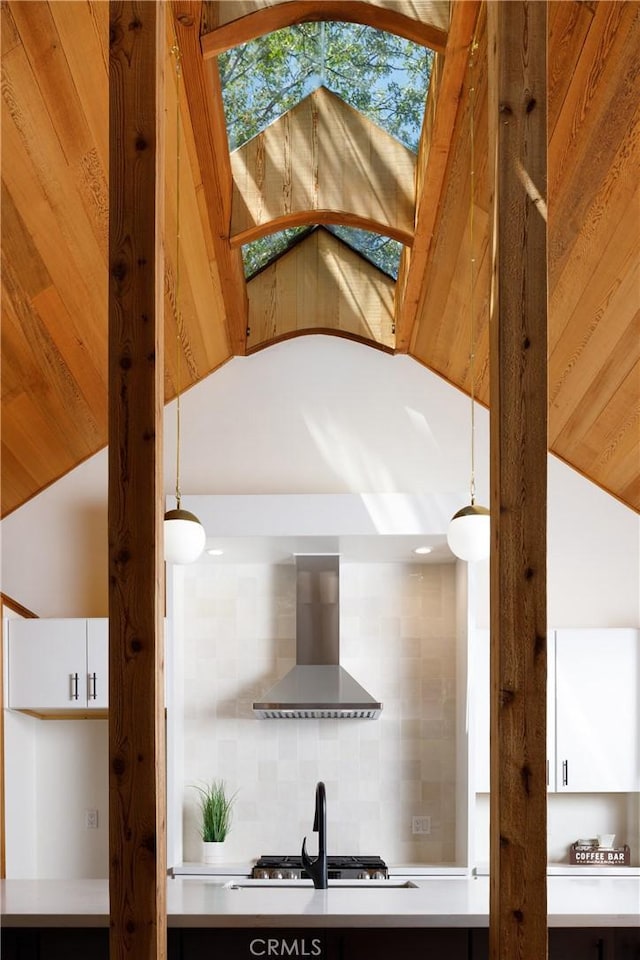 interior details with wall chimney range hood, backsplash, and sink