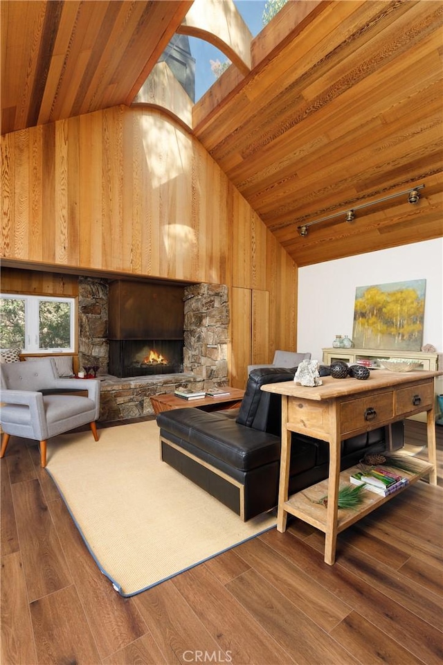 living room with vaulted ceiling, wooden ceiling, a fireplace, hardwood / wood-style floors, and wood walls