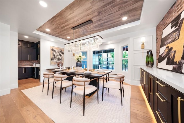 dining room featuring light wood-type flooring and a tray ceiling