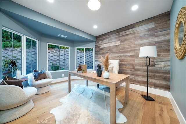 office area with light hardwood / wood-style flooring, a healthy amount of sunlight, and wood walls