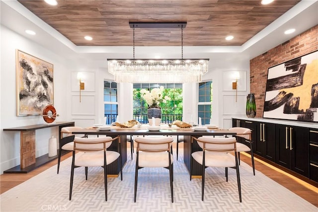 dining area featuring a notable chandelier, light hardwood / wood-style floors, wooden ceiling, and a tray ceiling