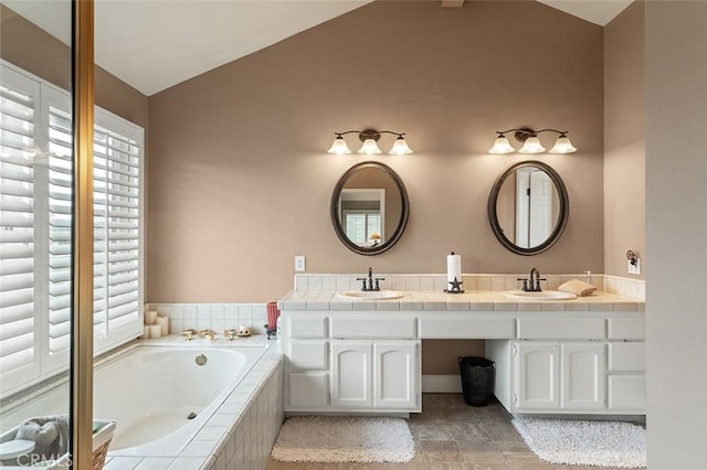 bathroom featuring lofted ceiling, vanity, and a relaxing tiled tub