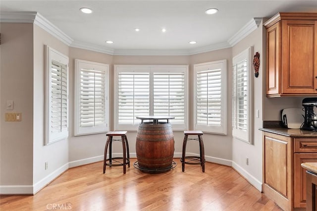 kitchen with ornamental molding, light hardwood / wood-style floors, and dark stone counters