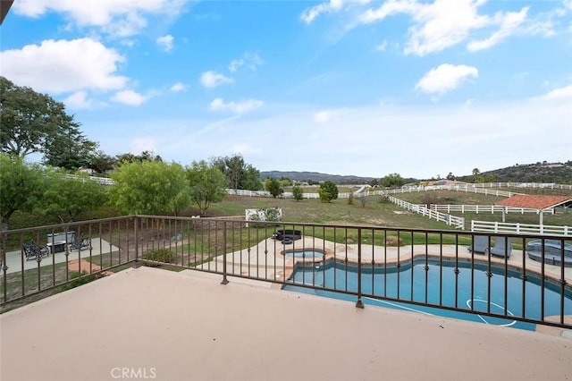 view of pool featuring an in ground hot tub, a rural view, and a patio