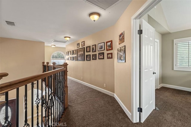 hallway with lofted ceiling and dark colored carpet