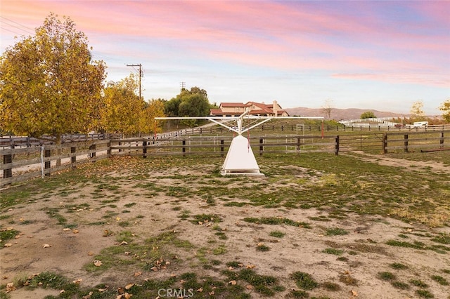 yard at dusk with a rural view and a mountain view