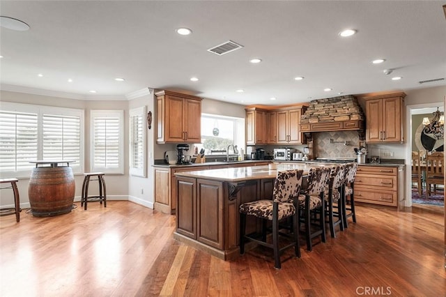 kitchen featuring dark hardwood / wood-style floors, a center island, custom exhaust hood, a breakfast bar, and sink