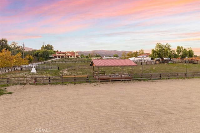 yard at dusk featuring a mountain view and a rural view