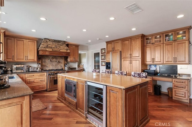 kitchen featuring custom exhaust hood, dark hardwood / wood-style floors, beverage cooler, and built in appliances