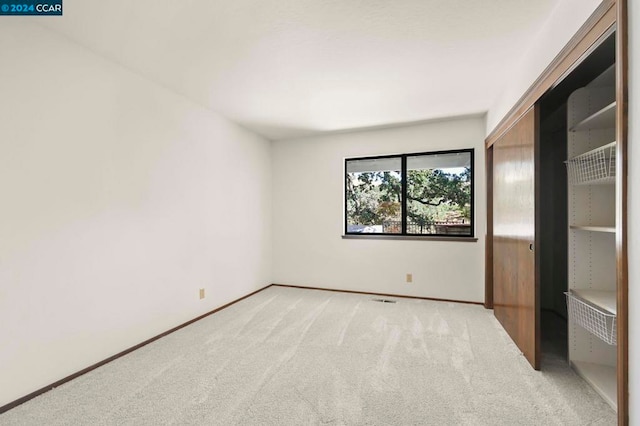 unfurnished bedroom featuring light carpet and a closet