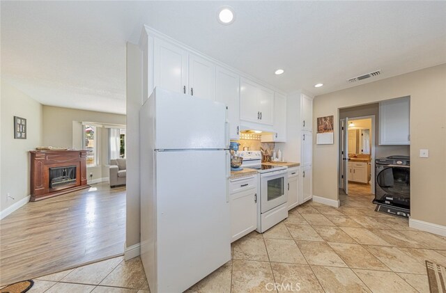 kitchen with light tile patterned floors, white appliances, white cabinets, and backsplash