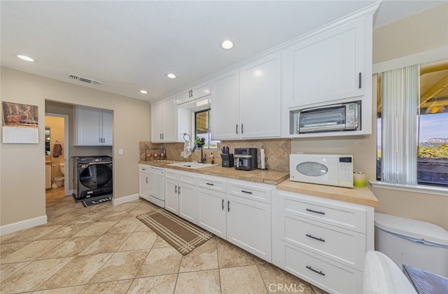 kitchen featuring washer / clothes dryer, tasteful backsplash, sink, white cabinets, and white appliances