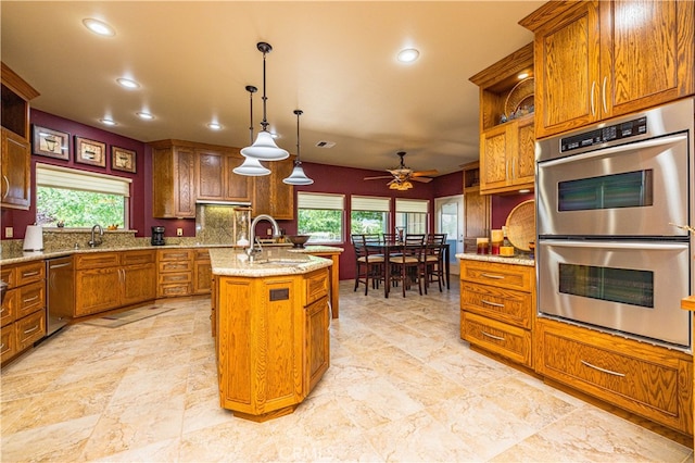 kitchen featuring stainless steel appliances, sink, decorative light fixtures, a healthy amount of sunlight, and a kitchen island with sink