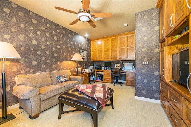 carpeted living room featuring ceiling fan, built in desk, and a textured ceiling