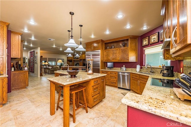 kitchen with pendant lighting, sink, light stone counters, and stainless steel appliances