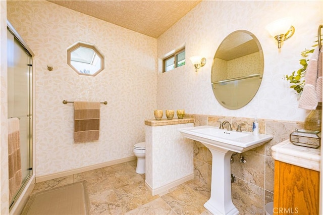 bathroom featuring a shower with door and toilet