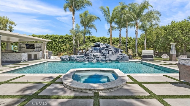 view of swimming pool with a patio area, an in ground hot tub, pool water feature, and exterior kitchen