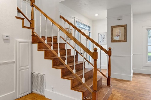 stairway with wood-type flooring and a wealth of natural light