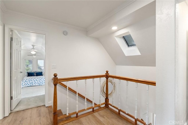 stairway with ornamental molding, lofted ceiling with skylight, and hardwood / wood-style floors