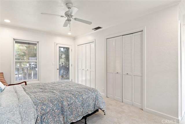 carpeted bedroom with multiple closets, ceiling fan, and ornamental molding