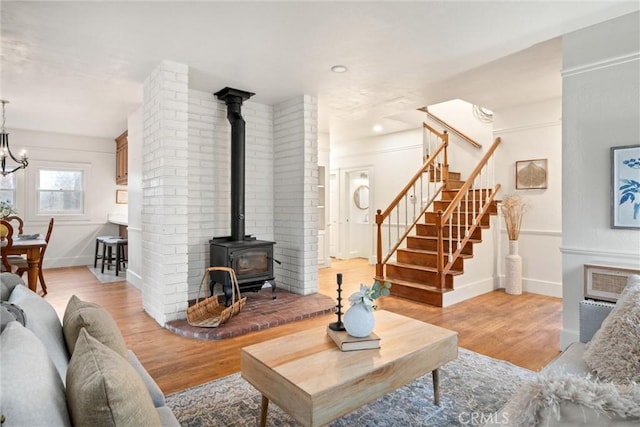 living room featuring an inviting chandelier, light hardwood / wood-style floors, and a wood stove